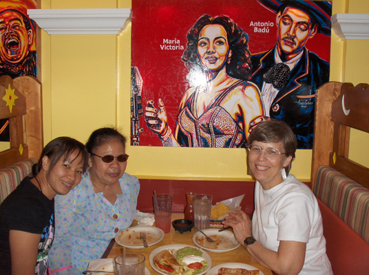 Ann, Nanta and Dona sit in a booth -- on the wall behind them is a drawing of Mexican singers.